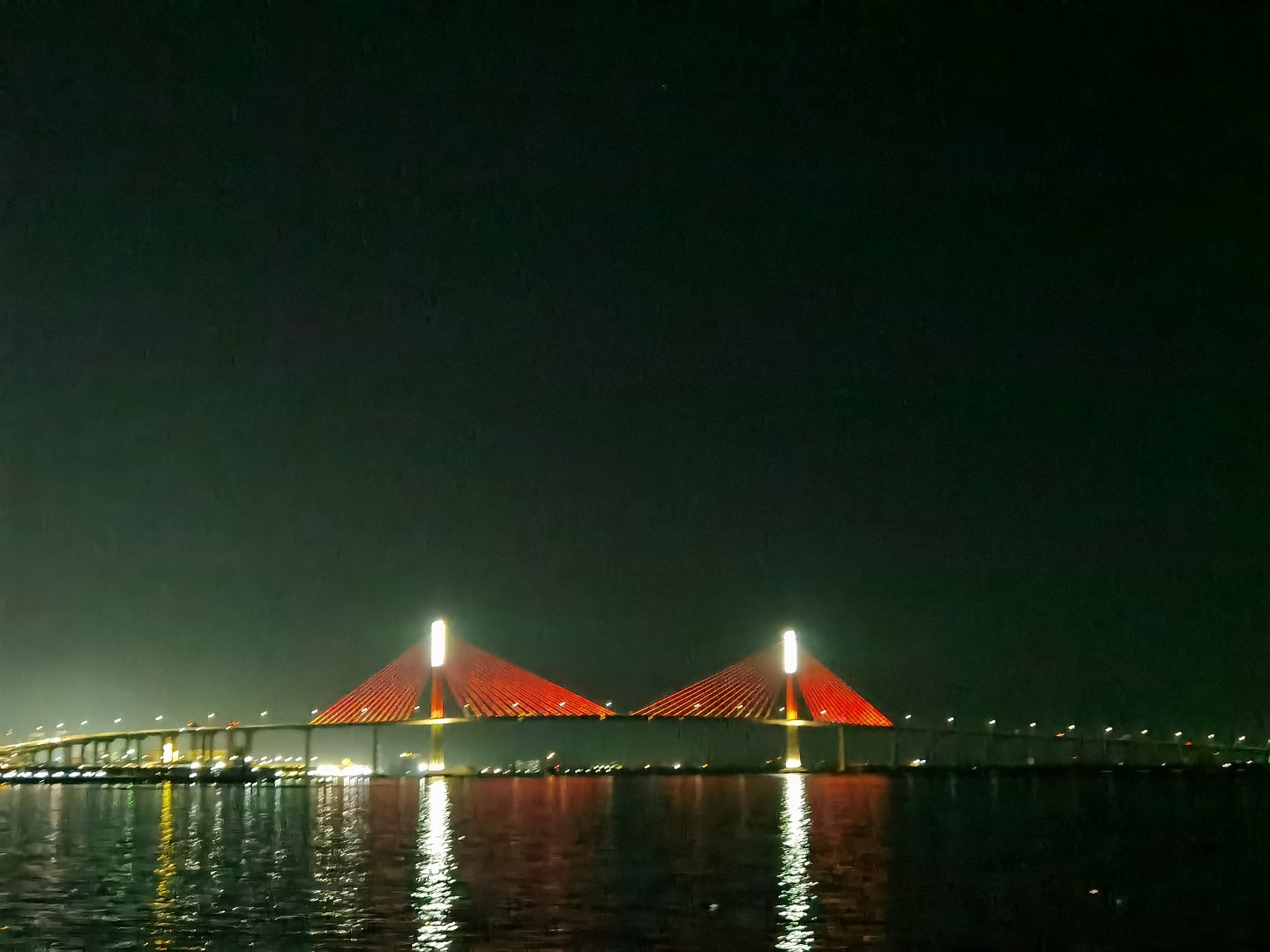 Cebu CCLEX bridge illuminated in red lights at night reflecting on water