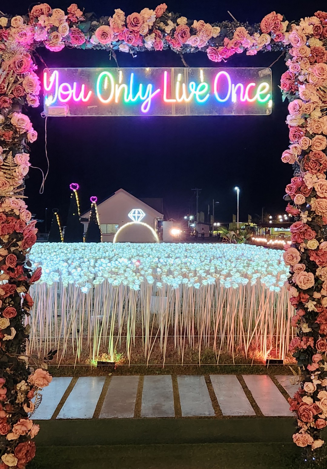 You Only Live Once neon sign with flower arch in Philippines night market